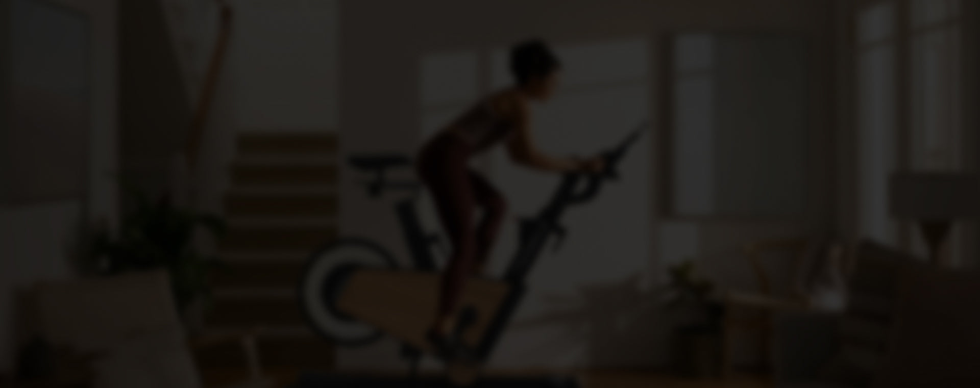 Frau trainiert auf einem eleganten, holzfarbenen Heimtrainer in einem modernen Wohnzimmer.
