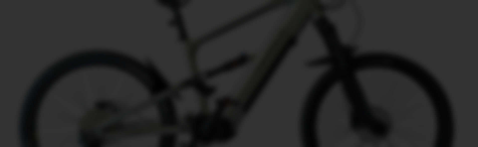 Dunkles, unscharfes Bild eines Mountainbikes mit Federung und breiten Reifen.