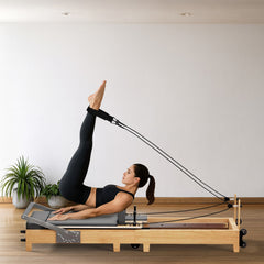 Frau trainiert am grauen TWHEELS Pilates Reformer aus Ahornholz im Home-Studio